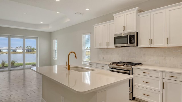 kitchen featuring appliances with stainless steel finishes, an island with sink, a water view, and sink