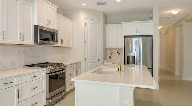 kitchen with backsplash, a center island with sink, sink, white cabinetry, and stainless steel appliances