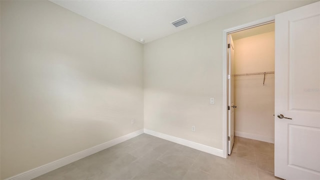 unfurnished bedroom featuring a closet, light tile patterned floors, and a walk in closet