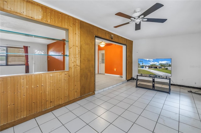 tiled spare room featuring ceiling fan and wooden walls