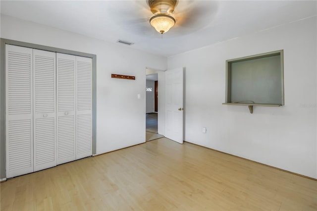 unfurnished bedroom with ceiling fan, a closet, and light hardwood / wood-style flooring