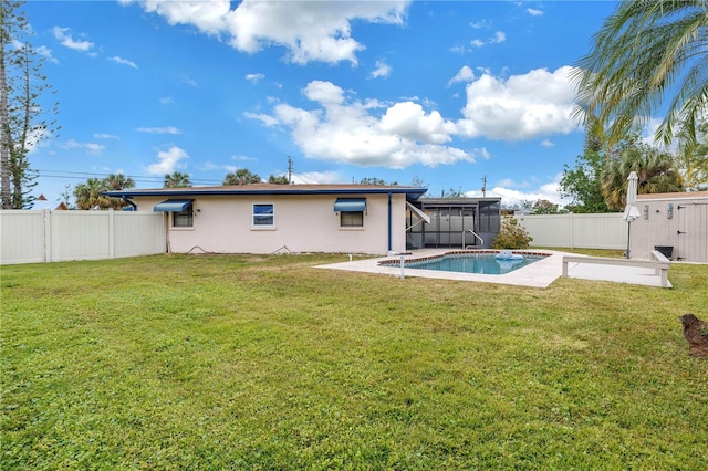 rear view of house with a fenced in pool and a yard