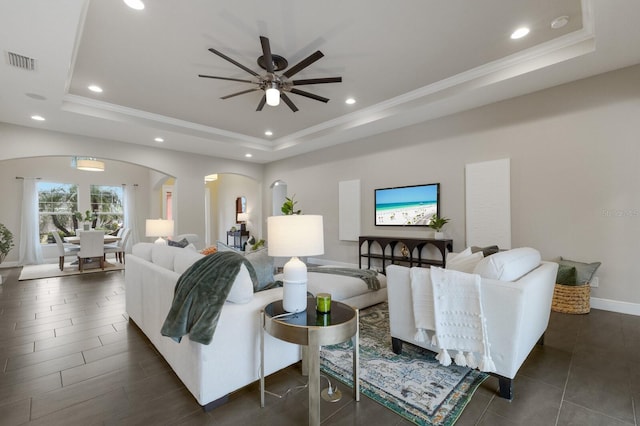 living room featuring ceiling fan and a tray ceiling