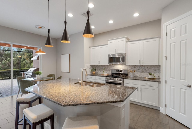 kitchen with sink, hanging light fixtures, white cabinets, and appliances with stainless steel finishes