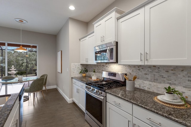 kitchen featuring stainless steel appliances, dark stone countertops, white cabinets, and decorative backsplash