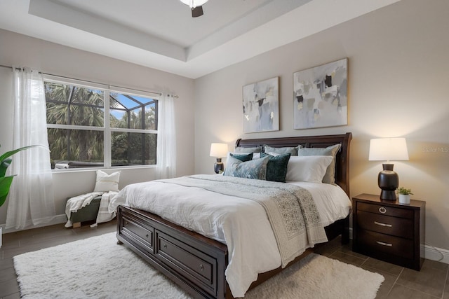 bedroom with baseboards, a tray ceiling, ceiling fan, and dark tile patterned flooring