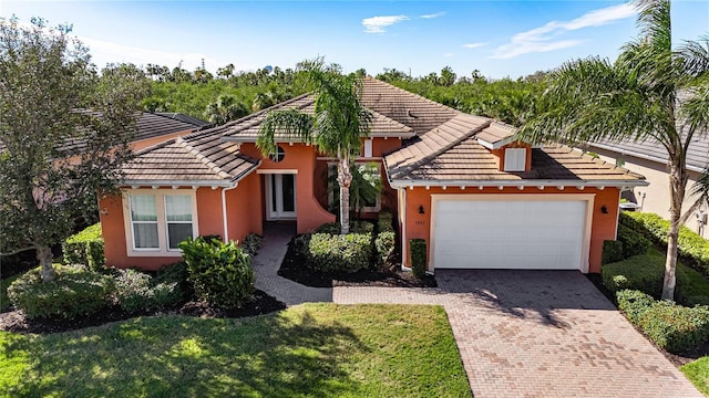 view of front of home with a tile roof, a front lawn, decorative driveway, and stucco siding