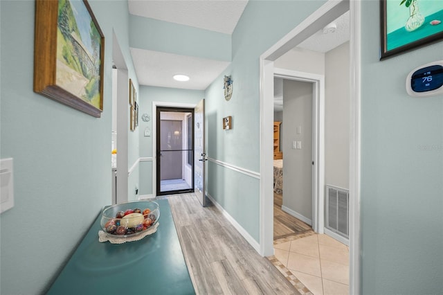 hall featuring light hardwood / wood-style flooring and a textured ceiling