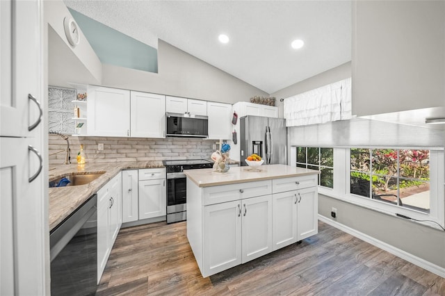 kitchen with vaulted ceiling, appliances with stainless steel finishes, dark hardwood / wood-style floors, sink, and white cabinets