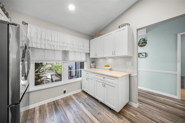 kitchen with white cabinetry, dark wood-type flooring, stainless steel fridge, and lofted ceiling