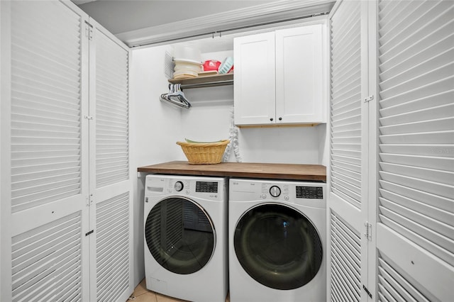 clothes washing area featuring washer and clothes dryer, cabinets, and light tile patterned flooring