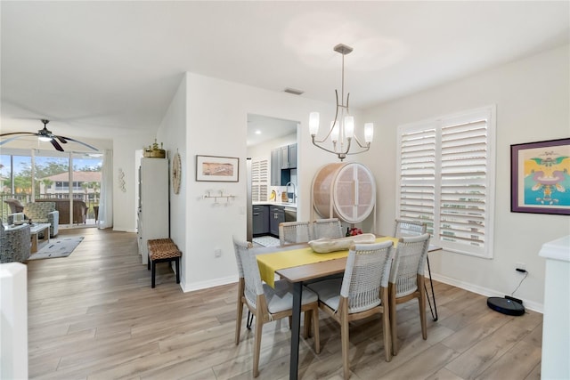 dining room featuring ceiling fan with notable chandelier, sink, and light wood-type flooring