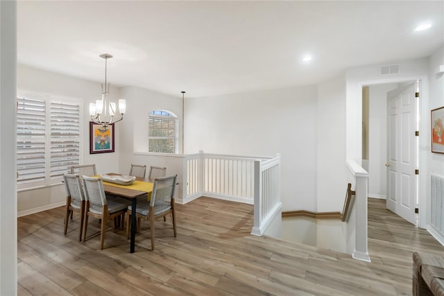 dining space with an inviting chandelier and light hardwood / wood-style flooring