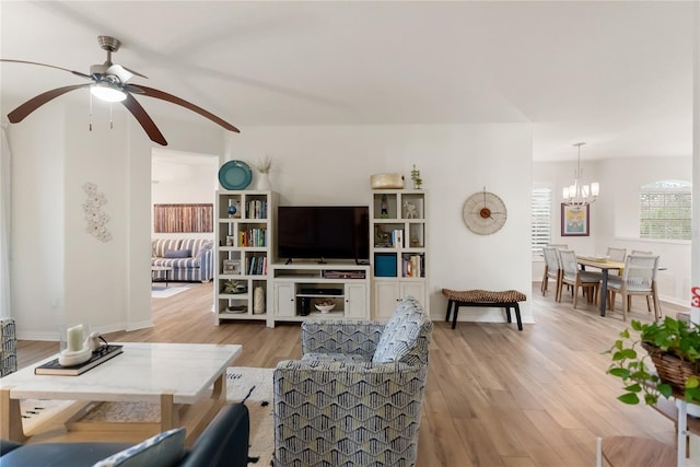 living room with light hardwood / wood-style floors and ceiling fan with notable chandelier