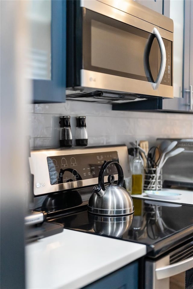 kitchen with blue cabinetry, decorative backsplash, and stainless steel appliances