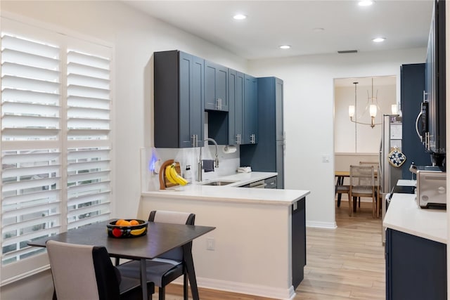 kitchen with a notable chandelier, light hardwood / wood-style floors, hanging light fixtures, blue cabinets, and sink