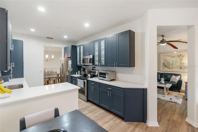 kitchen with ceiling fan, blue cabinetry, sink, light hardwood / wood-style flooring, and stainless steel appliances