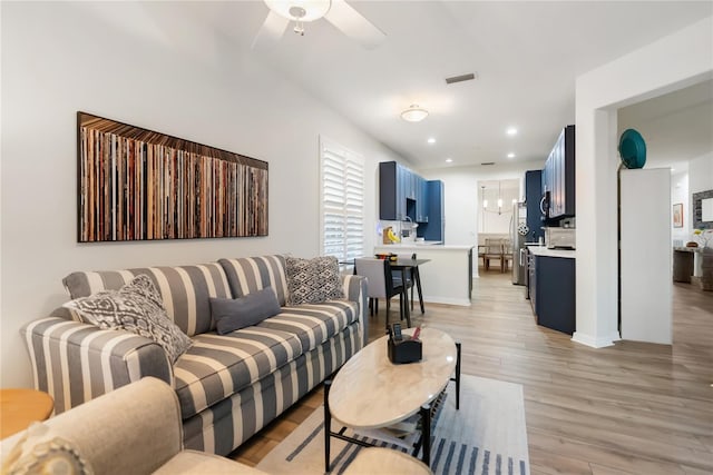 living room with light hardwood / wood-style floors and ceiling fan with notable chandelier