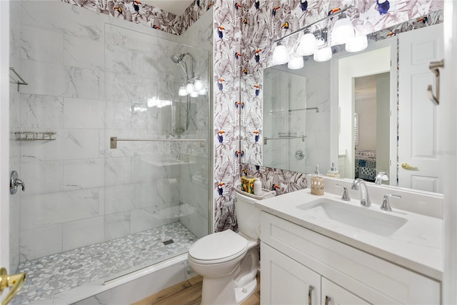 bathroom featuring a shower with door, toilet, and vanity