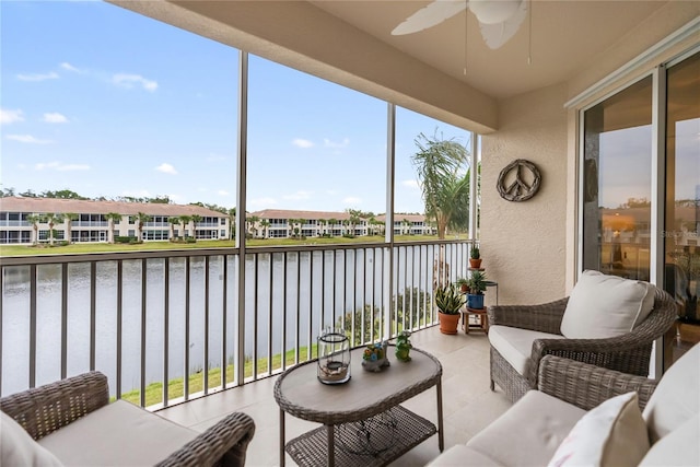 sunroom with ceiling fan and a water view