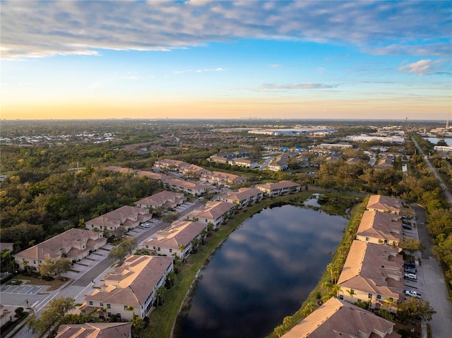 aerial view at dusk featuring a water view