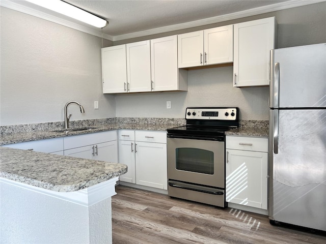 kitchen featuring kitchen peninsula, sink, stainless steel appliances, ornamental molding, and white cabinets