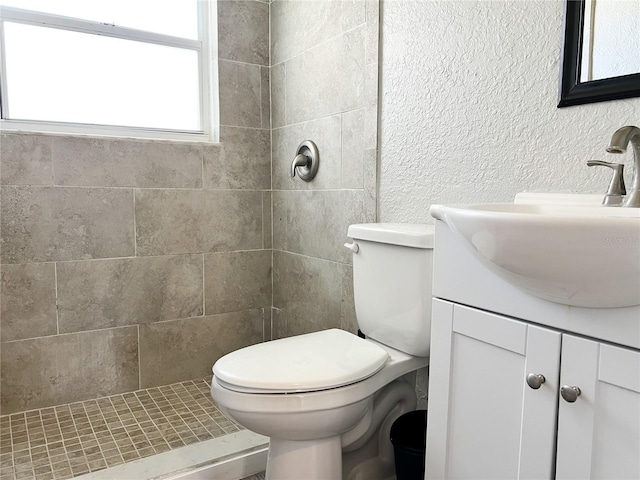 bathroom with toilet, vanity, and tiled shower