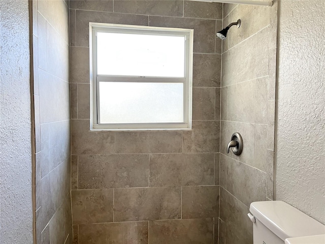 bathroom with toilet and tiled shower