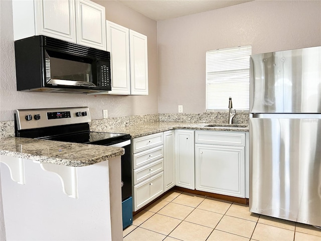 kitchen featuring light stone countertops, appliances with stainless steel finishes, white cabinetry, sink, and light tile patterned floors