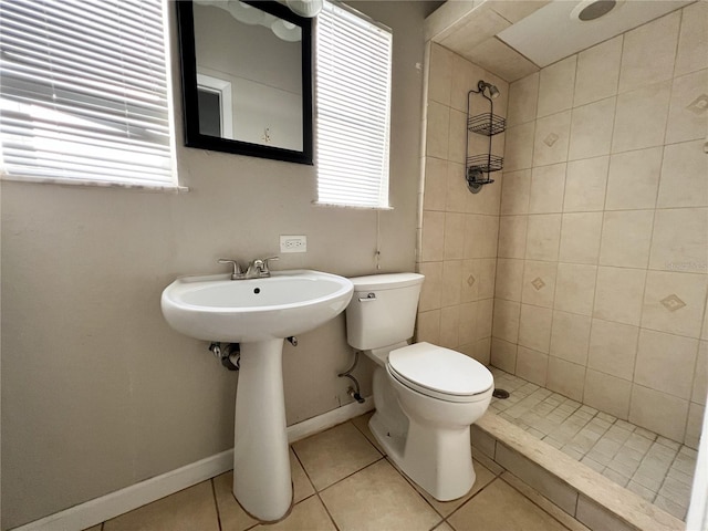 bathroom featuring toilet, a tile shower, and tile patterned floors