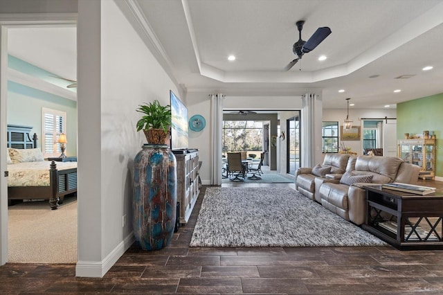 living room featuring crown molding, a tray ceiling, and ceiling fan