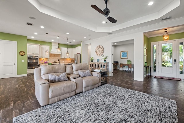 living room featuring crown molding, ceiling fan, a tray ceiling, and sink