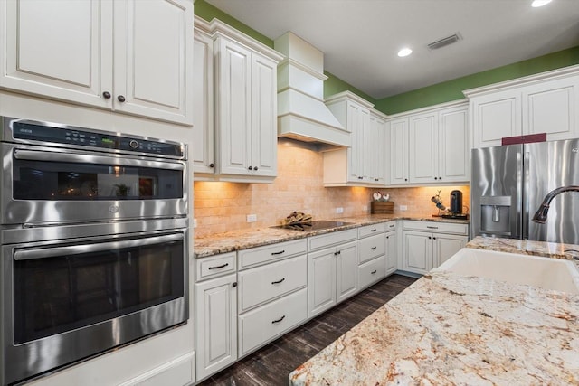 kitchen with sink, appliances with stainless steel finishes, dark hardwood / wood-style flooring, custom range hood, and white cabinets