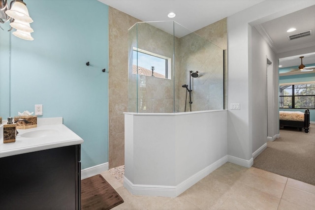 bathroom featuring crown molding, ceiling fan, vanity, a tile shower, and tile patterned floors