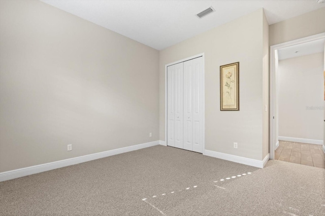 unfurnished bedroom featuring light colored carpet and a closet