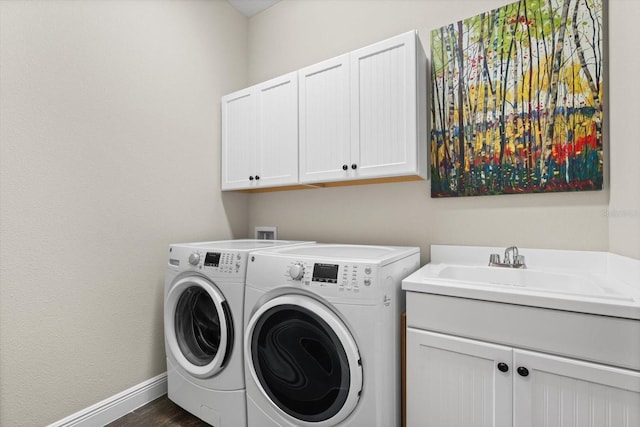 laundry area featuring dark hardwood / wood-style flooring, sink, washer and clothes dryer, and cabinets