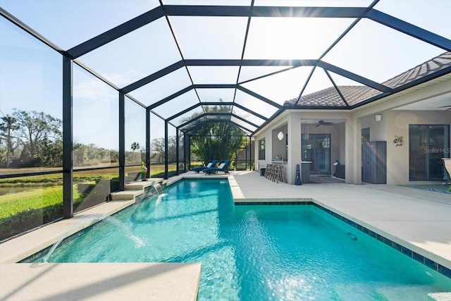 view of pool featuring ceiling fan, a patio, glass enclosure, a bar, and pool water feature