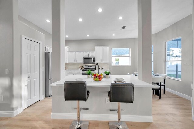 14146 Cattle Egret Pl, Bradenton, FL 34202 - kitchen with a kitchen breakfast bar, white cabinets, stainless steel appliances, and an island with sink