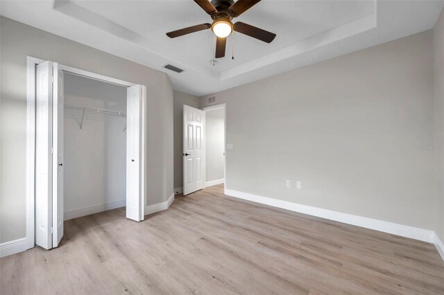 14146 Cattle Egret Pl, Bradenton, FL 34202 - unfurnished bedroom with a raised ceiling, ceiling fan, a closet, and light hardwood / wood-style floors