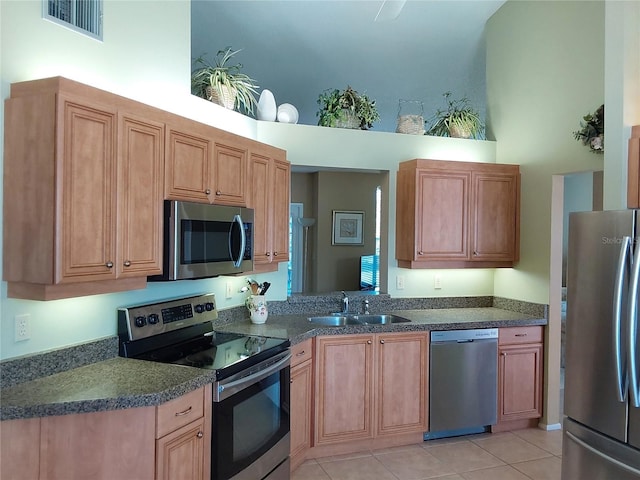 kitchen featuring light tile patterned flooring, appliances with stainless steel finishes, a towering ceiling, and sink