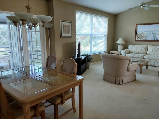 carpeted dining space featuring ceiling fan with notable chandelier