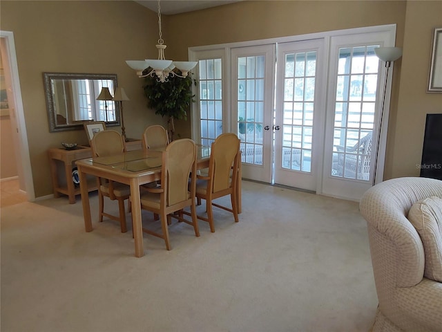 carpeted dining space with a healthy amount of sunlight, french doors, and a chandelier