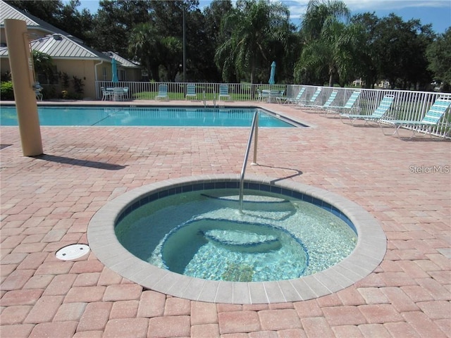 view of pool with a hot tub and a patio