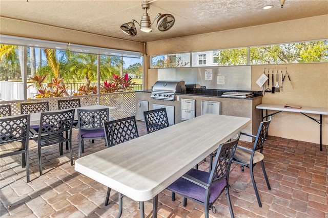 view of patio featuring ceiling fan, area for grilling, an outdoor kitchen, and a bar