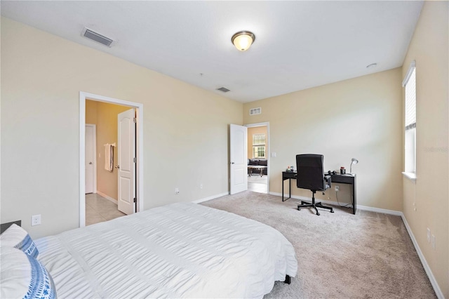 bedroom with ensuite bathroom and light carpet