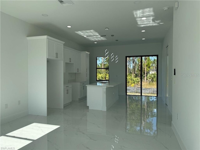 kitchen featuring a kitchen island, white cabinetry, and sink