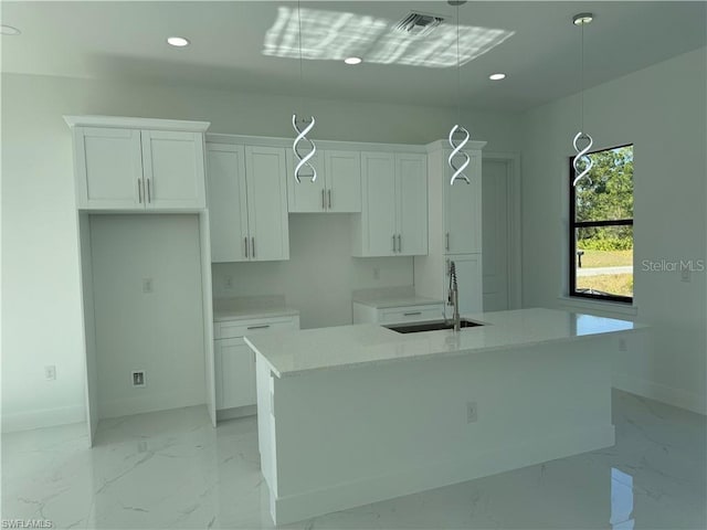 kitchen featuring a kitchen island with sink, sink, and white cabinetry