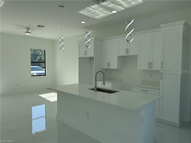 kitchen featuring sink, white cabinets, hanging light fixtures, and a kitchen island with sink