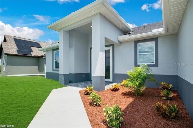 view of exterior entry with a yard and solar panels