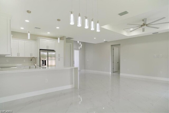 kitchen featuring white cabinets, sink, pendant lighting, ceiling fan, and stainless steel fridge